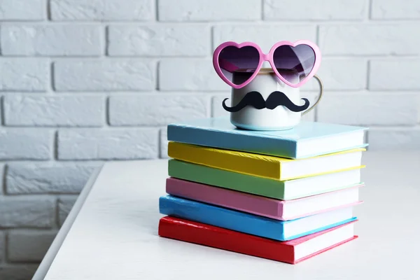 Färgade böcker och cup med mustasch — Stockfoto