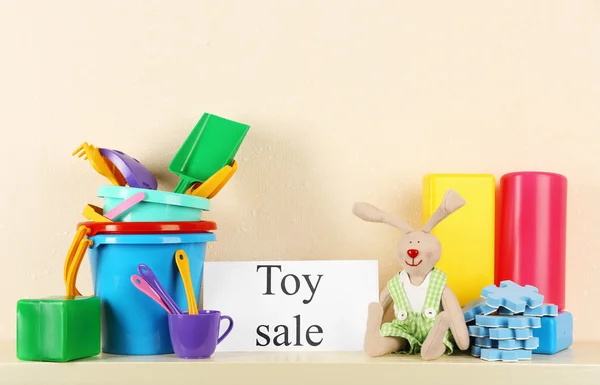 Hračky pro prodej na polici, na světlé zdi pozadí — Stock fotografie