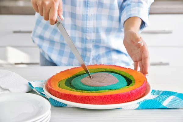 Frau schneidet Regenbogenkuchen — Stockfoto