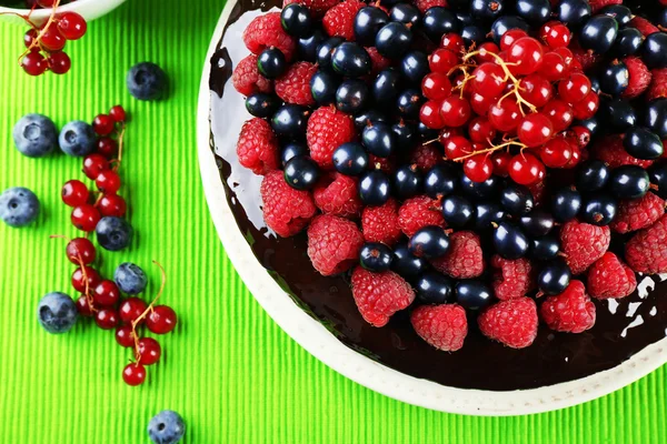 Deliziosa torta al cioccolato con bacche estive sulla tovaglia verde, vista dall'alto — Foto Stock