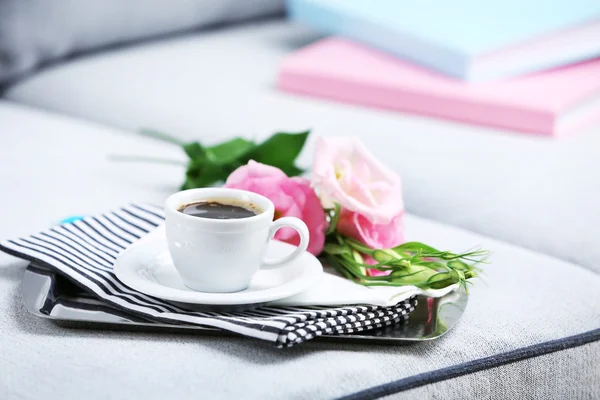 Cup of coffee with flowers on tray on sofa in room — Stock Photo, Image