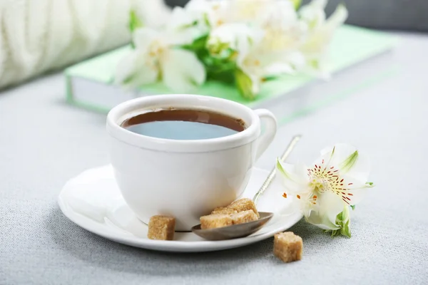 Tazza di caffè con zucchero grumo e fiori sul divano — Foto Stock