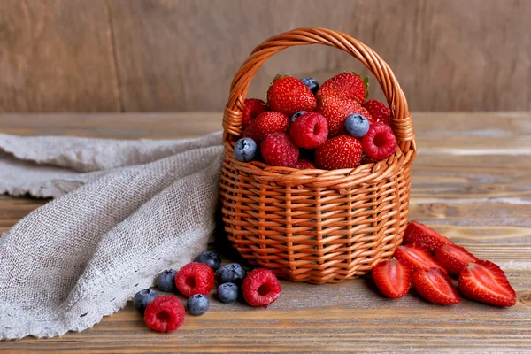 Tasty ripe berries in basket on wooden table close up — Stock Photo, Image