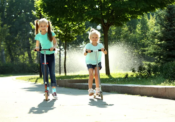 Small girls riding on scooters — Stock Photo, Image