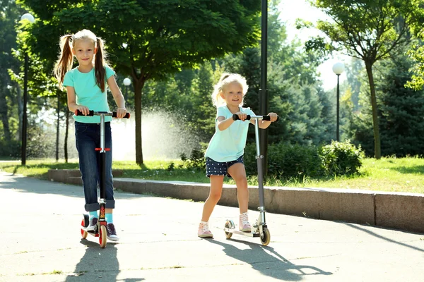 Small girls riding on scooters — Stock Photo, Image