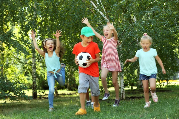 Glückliche aktive Kinder spielen mit Fußball im Park — Stockfoto