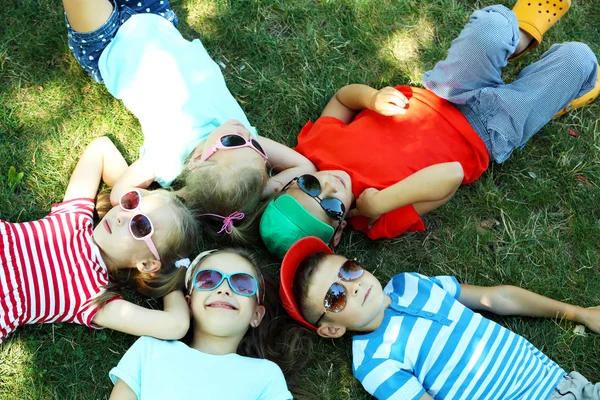 Niños activos felices tumbados sobre hierba verde en el parque — Foto de Stock