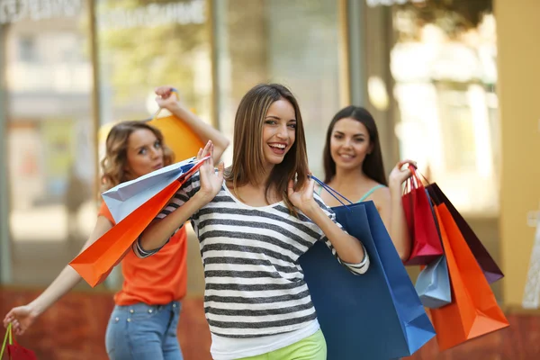 Vackra unga kvinnor med shoppingväskor på stadens gata — Stockfoto