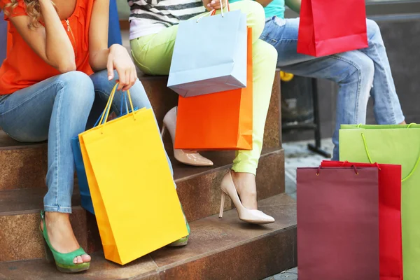 Jovens mulheres bonitas com sacos de compras sentados em passos — Fotografia de Stock