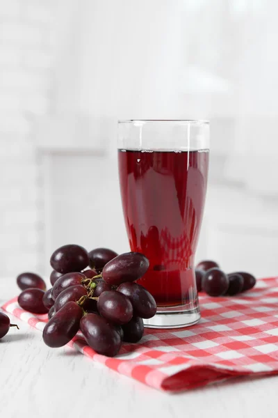 Glass of juice and ripe grapes in bowl on wooden table — Stock Photo, Image