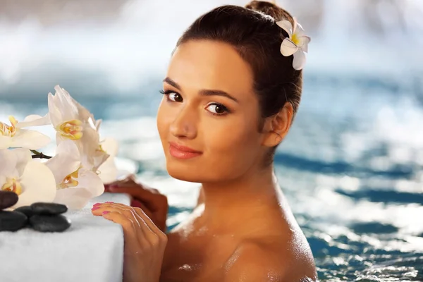 Mulher bonita com flores na piscina — Fotografia de Stock