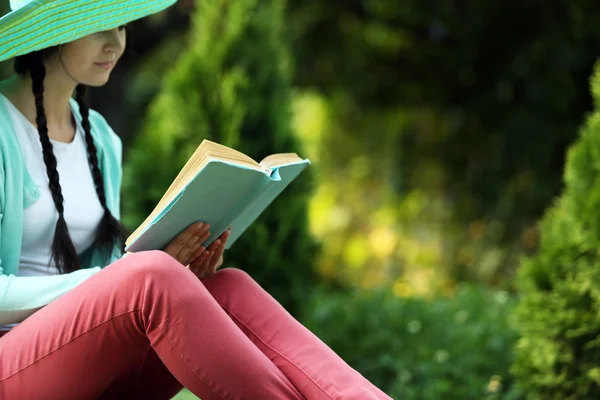 屋外の緑の草の上に座って本を持つ若い女性 — ストック写真
