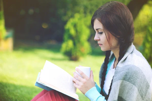 Junge Frau mit Buch auf grünem Gras im Freien — Stockfoto