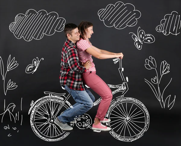 Lustiges junges Paar fährt Fahrrad, auf schwarzem Hintergrund — Stockfoto