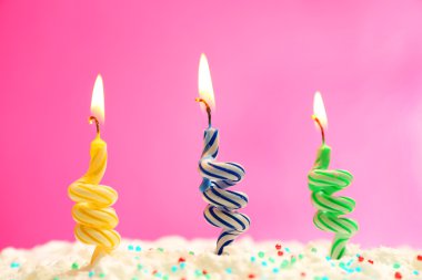 Renkli arkaplanda mumlar olan doğum günü pastası