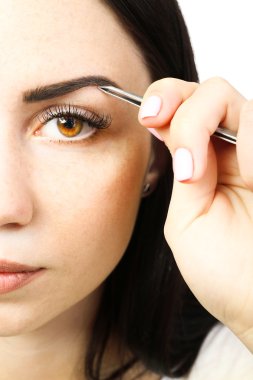 Cımbızla kaş yolan genç bir kadın. Yaklaş.