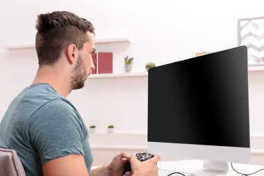 Genç adam evde bilgisayar oyunu oynuyor.