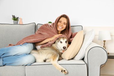 Malamute köpek odasında kanepede yatan genç kadın