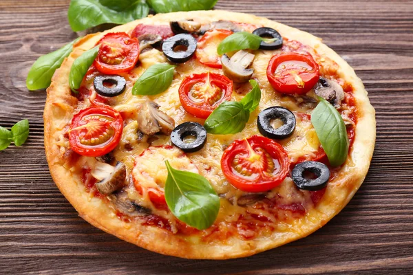 Pizza saborosa com legumes e manjericão na mesa de perto — Fotografia de Stock