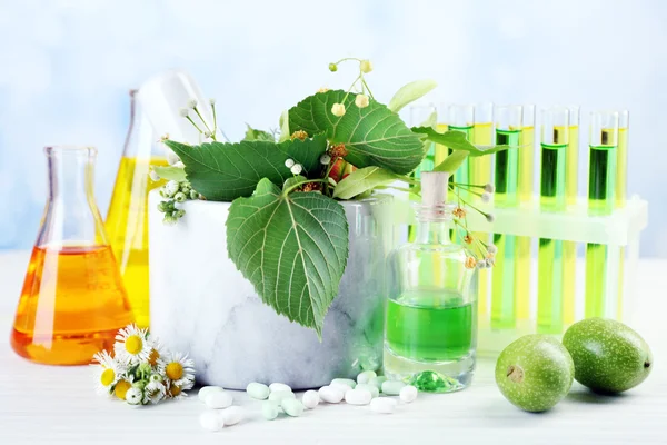 Herbs in mortar, test tubes and pills,  on table, on light background — Stock Photo, Image