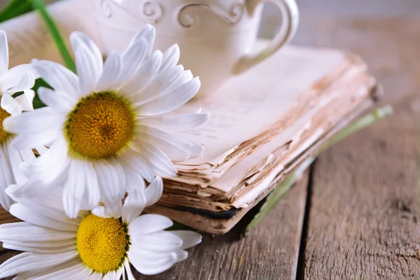 旧书的美丽的花朵和杯茶木制的桌子上关闭 — 图库照片