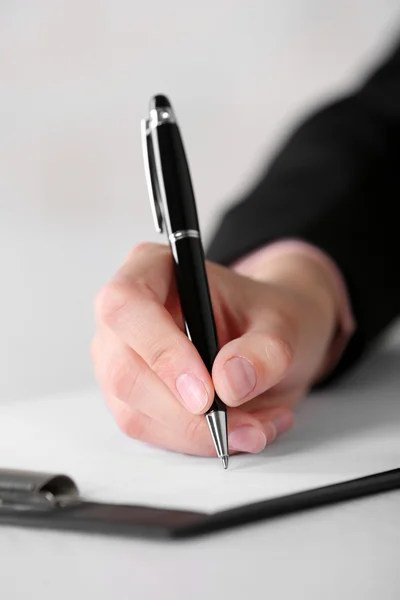 Female hand with pen writing on paper at workplace — Stock Photo, Image