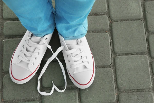 Pés femininos em sapatos de goma no fundo de asfalto — Fotografia de Stock