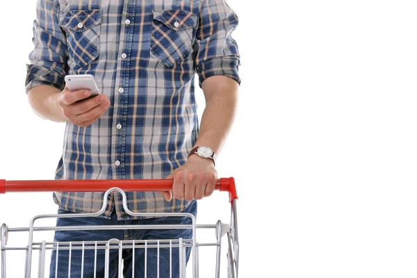Young man holding mobile phone and shopping cart isolated on white — Stock Photo, Image
