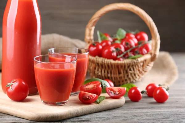 Botella llena y vasos de jugo de tomate con verduras en la mesa de madera de cerca — Foto de Stock