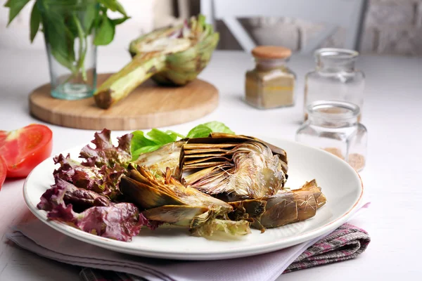 Carciofi arrosto su piatto, su fondo tavola cucina — Foto Stock