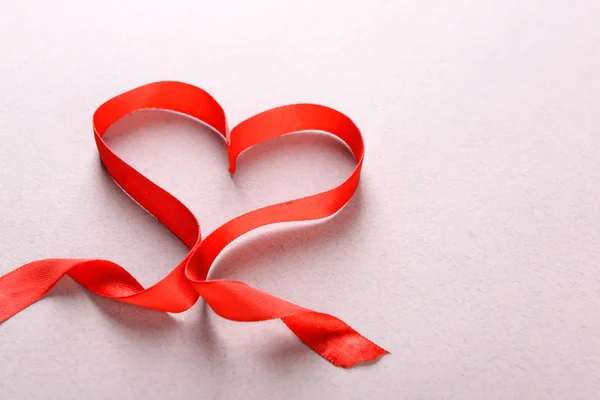 Ruban rouge en forme de coeur sur fond texturé clair — Photo