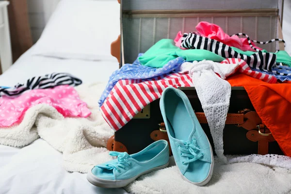 Resväska med kläder på sängen i rummet — Stockfoto