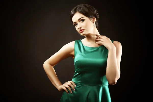 Приваблива жінка в зеленому платті на темному тлі — стокове фото