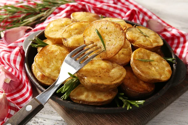 Läckra bakad potatis med rosmarin i stekpanna på bordet på nära håll — Stockfoto