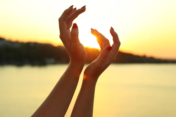 Las manos femeninas sobre el fondo del cielo soleado — Foto de Stock