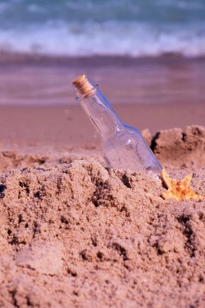 Bericht in fles op zand op zee achtergrond — Stockfoto