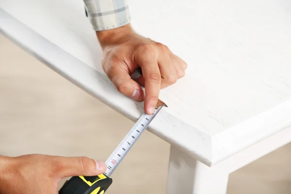 Jeune homme mesurant des meubles de maison avec ruban à mesurer, gros plan — Photo