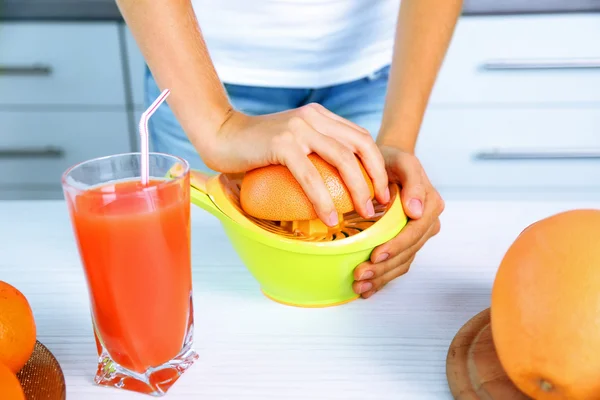 Jeune femme utilisant un pressoir aux agrumes, préparant du jus d'orange — Photo