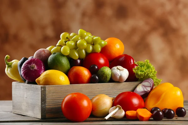 Sterty o świeże owoce i warzywa w skrzyni na drewnianym stole z bliska — Zdjęcie stockowe