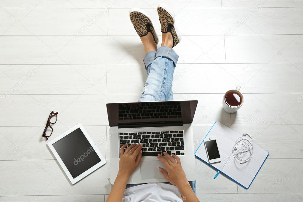 Top view of young woman sitting on floor with laptop