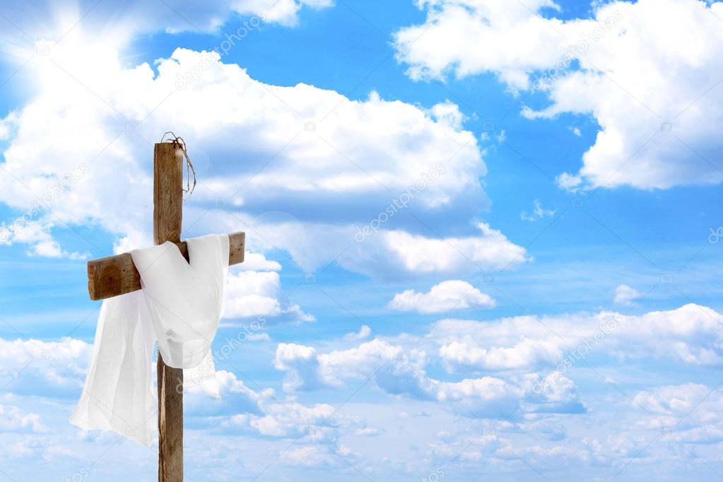 Cross with crown of thorns and cloth, on blue sky background
