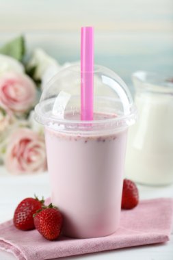 Milkshake hafif ahşap arka plan üzerinde plastik bardak