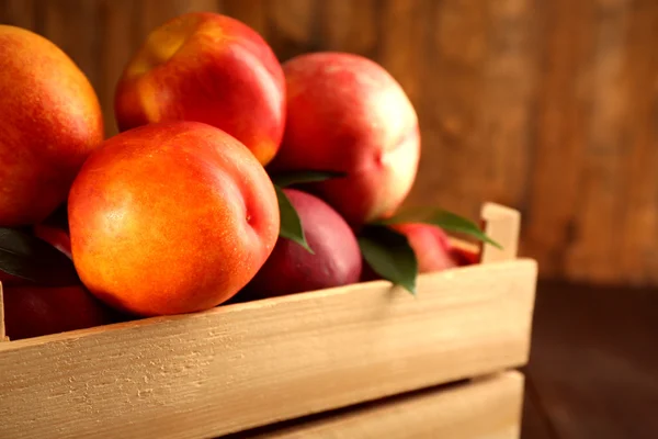 Fresh peaches in crate on wooden background — Stock Photo, Image