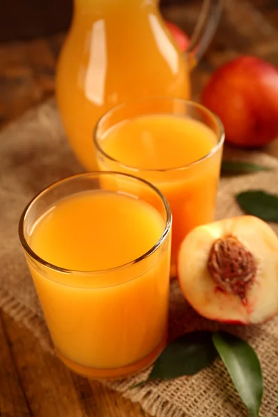 Pêches mûres et verre de jus sur fond de bois — Photo