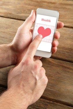 Hands holding smart mobile phone with health book app on the screen. clipart