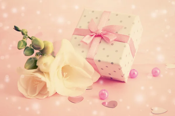 Hermosa pequeña caja de regalo y flor de freesia sobre fondo rosa —  Fotos de Stock