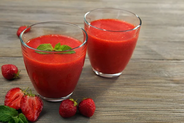 Glasögon av jordgubb smoothie med bär på träbord nära håll — Stockfoto