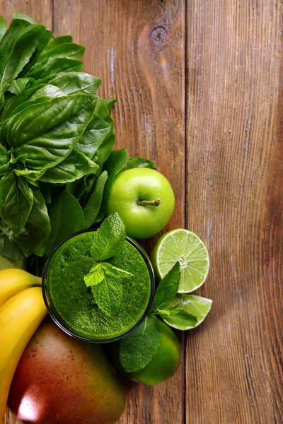 Green healthy juice with fruits and herbs on wooden table close up — Stock Photo, Image