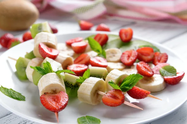 Fresh fruits on skewers in plate on table, closeup — Stock Photo, Image