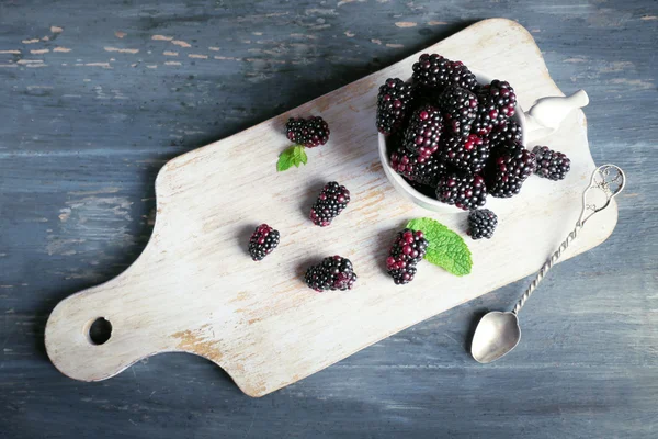 Heap of sweet blackberries with mint in cup on table close up — Stock Photo, Image